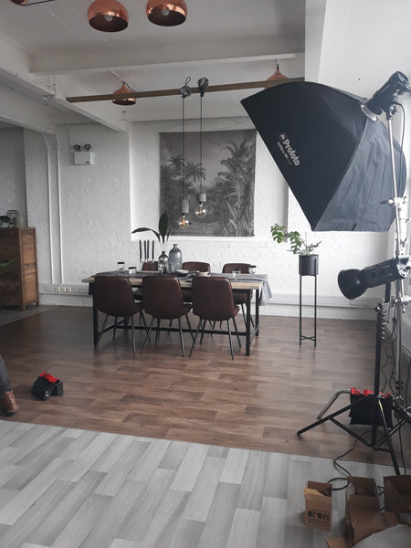 Our Amalfi Industrial H-Bar Oak Dining Table is surrounded by props and camera equipment, and ready to get its picture taken in our studio.