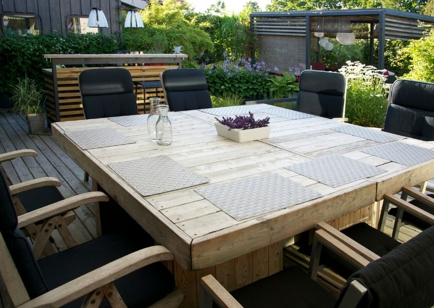 Outdoor square rustic dining table with wooden chairs and outdoor bar area