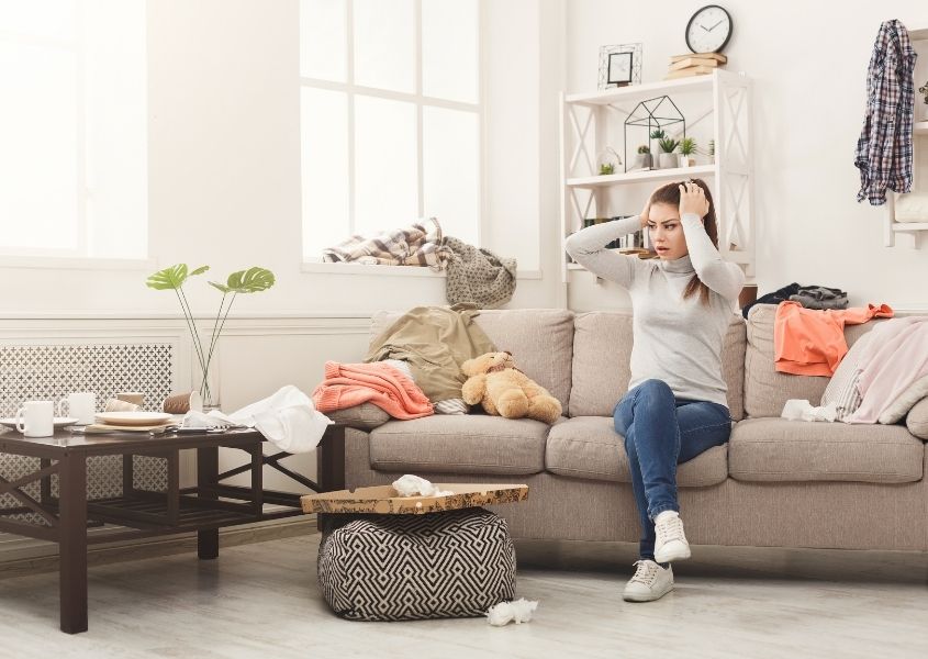 woman in messy living room with hands on her head for how to spring clean your home fast blog