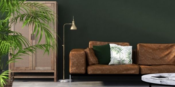 Brown leather sofa with floor lamp and dark green walls