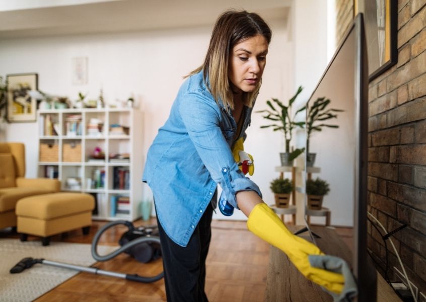 woman cleaning television for How to spring clean your home fast: a cheat's guide to cleaning blog post