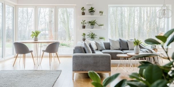 Bright living room with grey l-shaped sofa and round dining room table