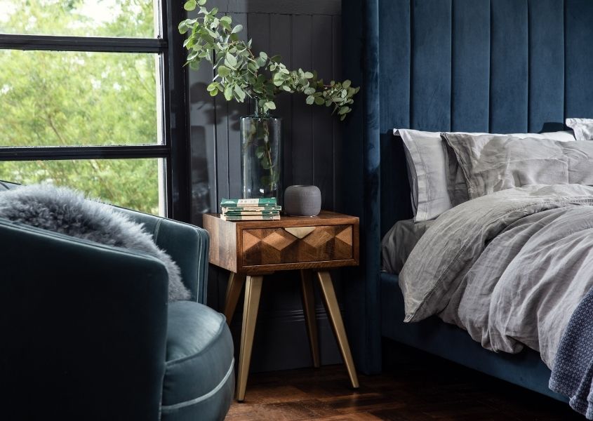mango wood bedside table next to fabric armchair