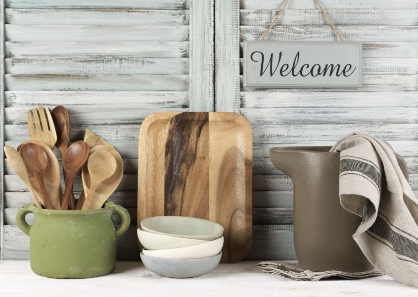 Whitewashed wooden shutters with welcome hanging sign and kitchen wooden utensils