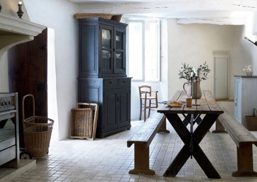 Farmhouse kitchen with large fireplace, long and thin rustic dining table and blue painted dresser