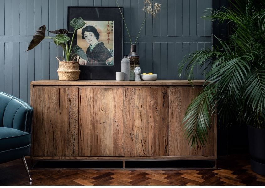 reclaimed wood sideboard with rustic wood beside large palm plant