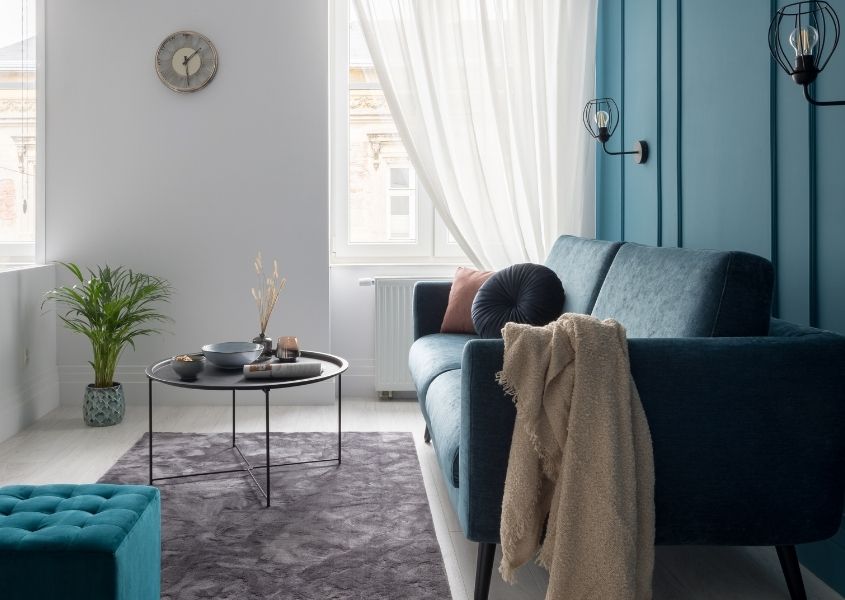 Narrow living room with blue painted wall and grey sofa