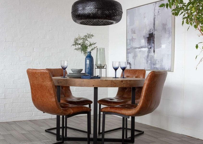 Round industrial dining table with tan leather dining chairs