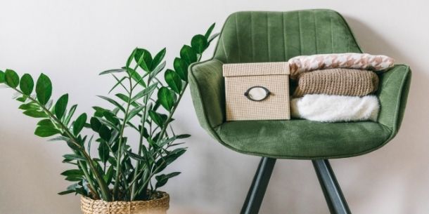 green velvet armchair with clothes on top for 5 ways to get better at decluttering