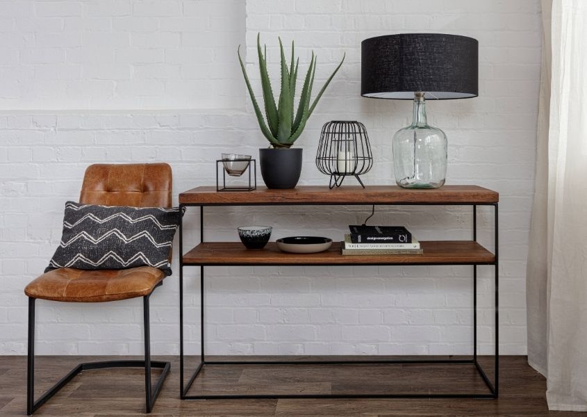 Industrial console table with brown leather chair and glass table lamp