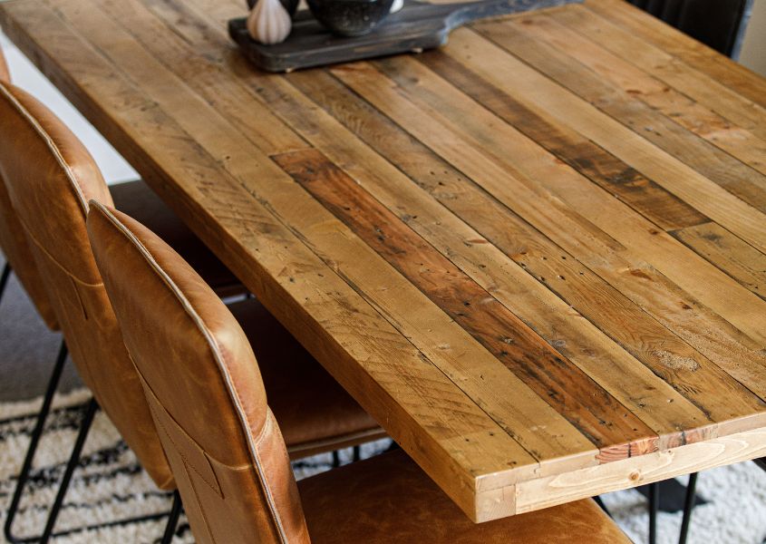 close up of reclaimed wood dining table with brown faux leather dining chairs