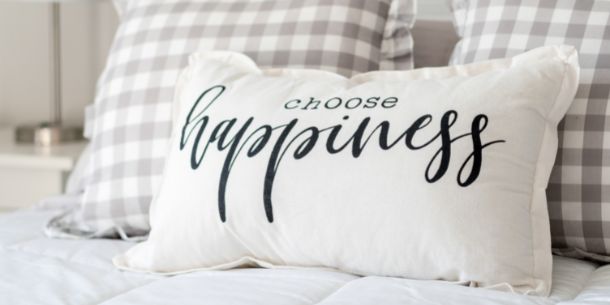 cushion with happiness written across it for 6 styling tips for a feel-good bedroom blog