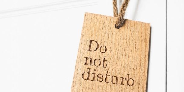Wooden do not disturb sign hanging on white door