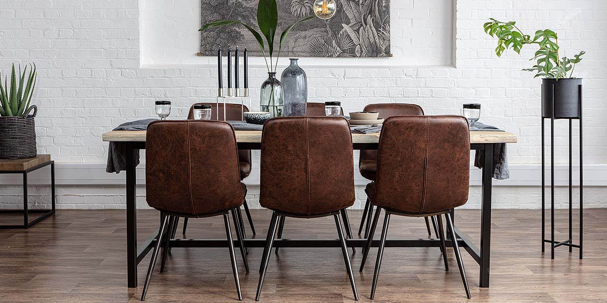 Dark brown faux leather chairs around a reclaimed wooden dining table with decor