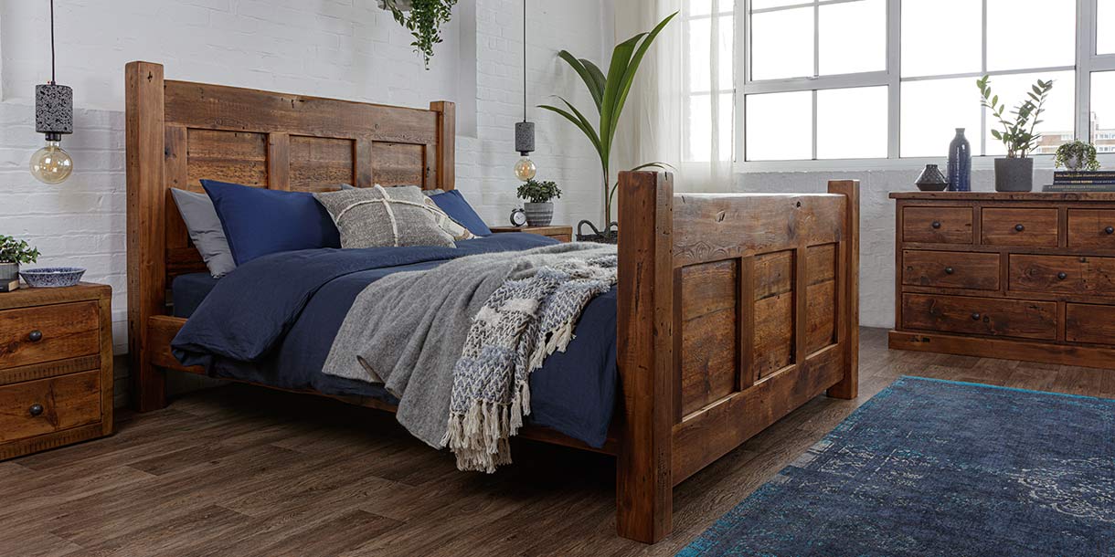 Reclaimed wooden beam bed with classic blue bedding and a blue rug