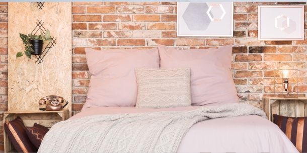 Bedroom with exposed brick wall and pink pillows