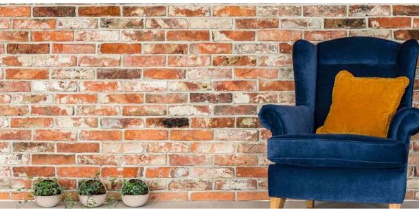 Brick wall with electric blue velvet armchair and yellow cushion