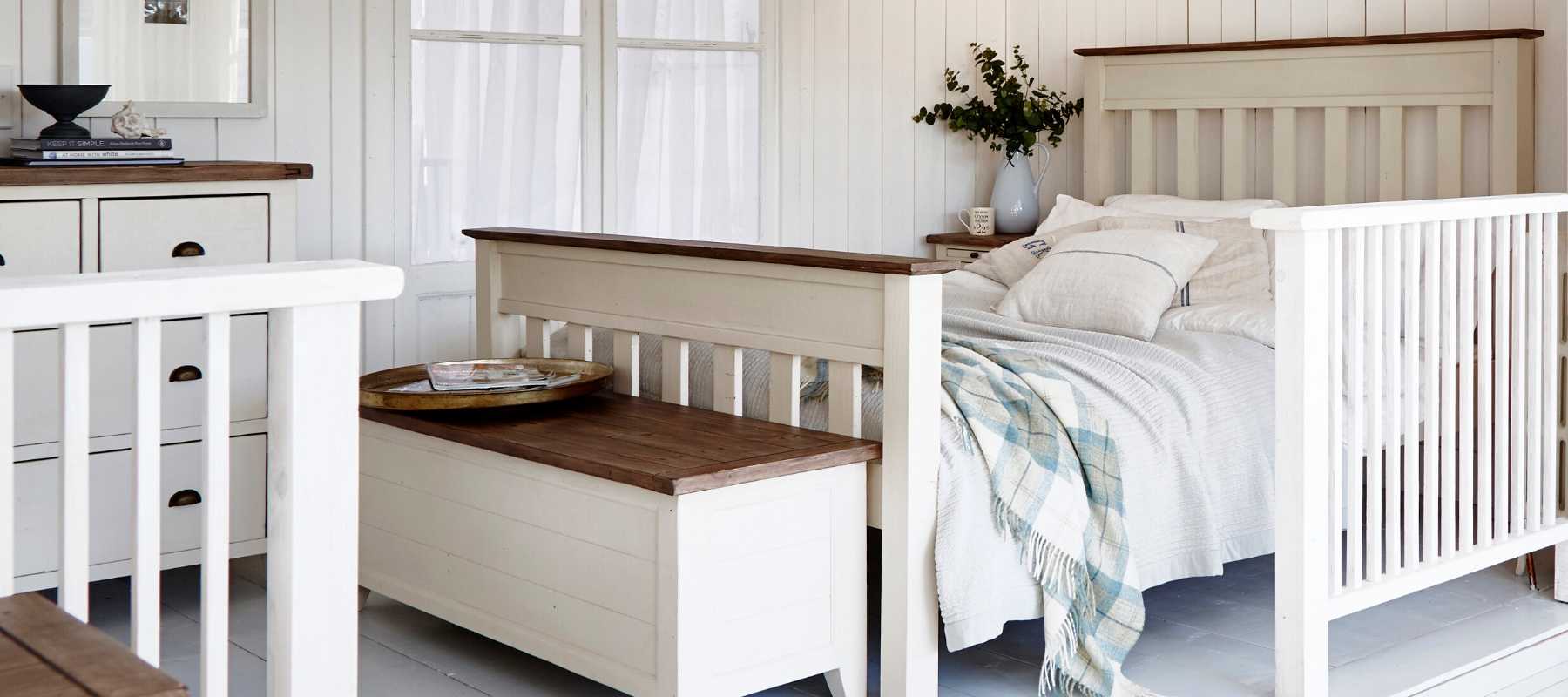 White blanket box and white wooden bed