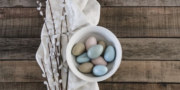 Coloured mini eggs in white pot on reclaimed wood table