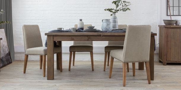 Reclaimed wood dining table with four natural coloured fabric dining chairs and dark grey linen runner