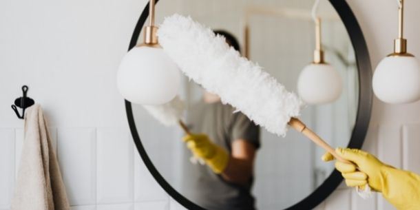 Woman dusting mirror for Top tips to keep your home clean and dust free blog