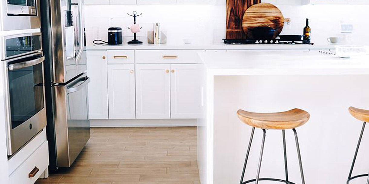 A white and sleek kitchen with light wooden flooring