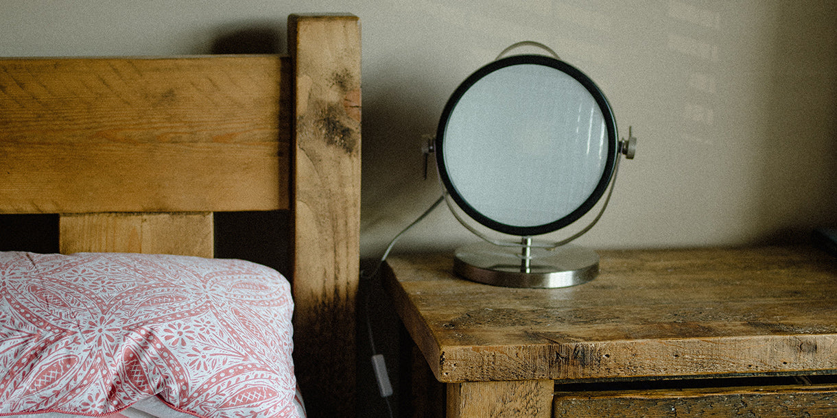 A rustic wooden bed with a matching bedside table and a table mirror