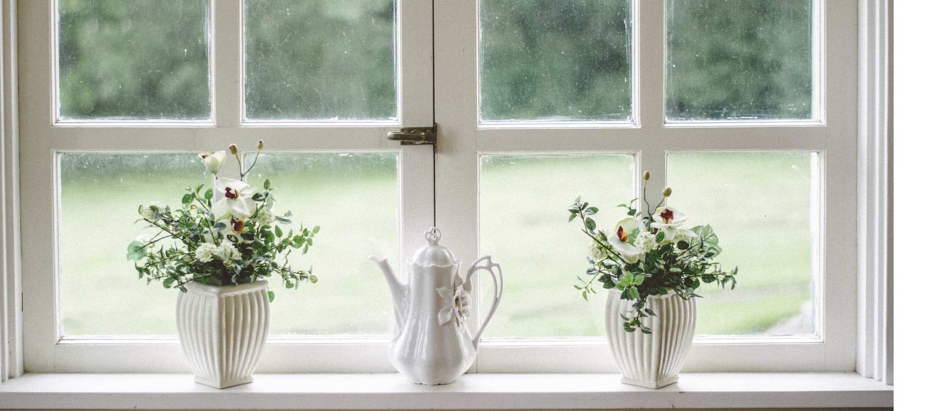 Spring flowers in white vase on window sill
