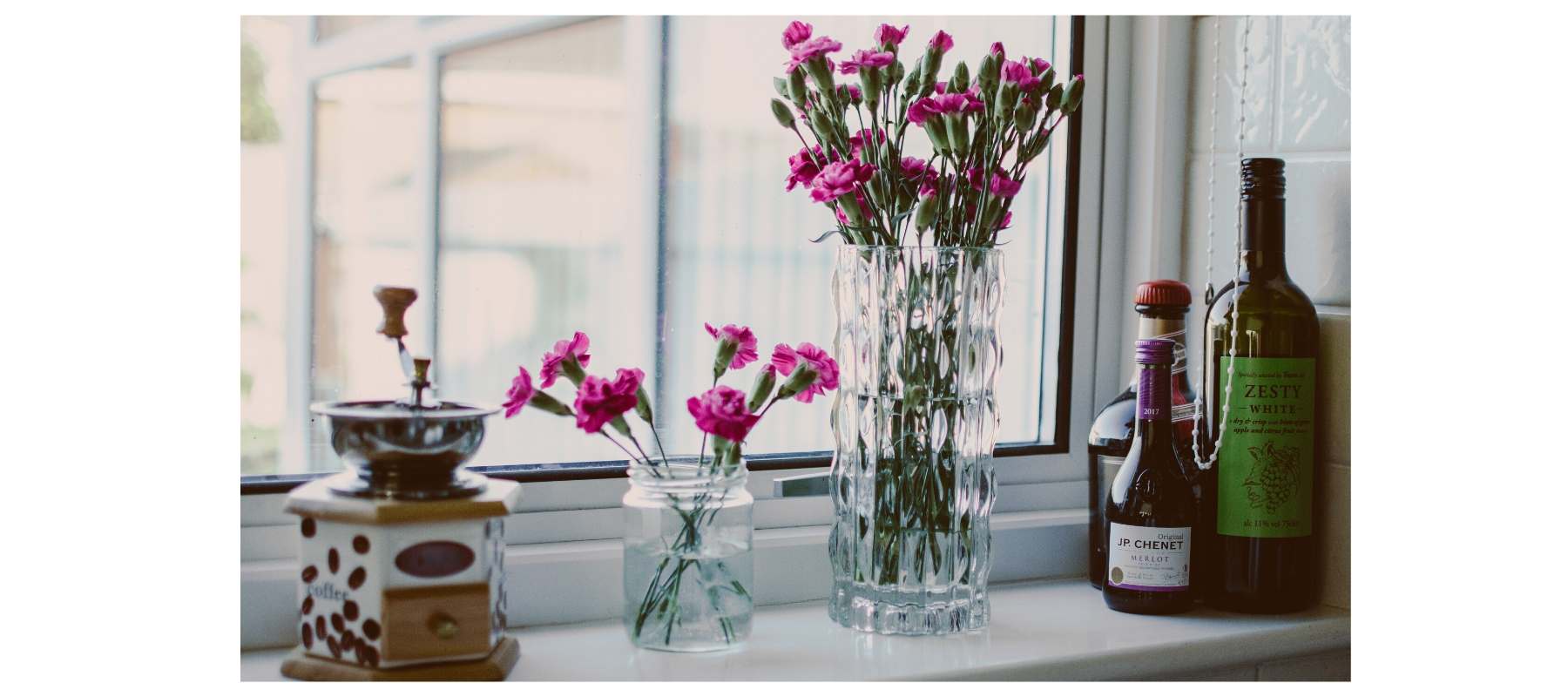 Pink flowers in glass jar on window sill