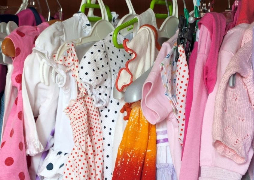 Colourful children's clothes on hangers in a wardrobe