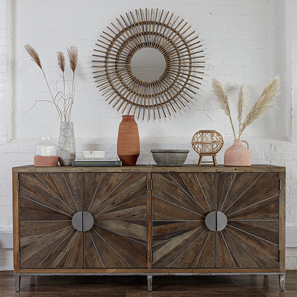 Rustic and industrial large sideboard with round metal handles, earthy decorative items on top and a bohemian sunburst mirror