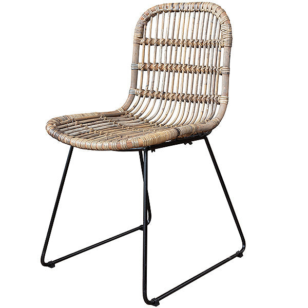 A bohemian dining chair made of rattan with black, industrial legs