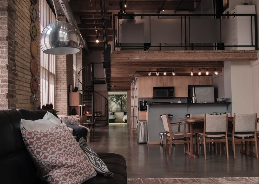 Open plan industrial living space with exposed brick walls and wooden dining table