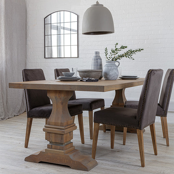 Reclaimed oak dining table with grey finish and dark grey velvet dining chairs, a curved window mirror and a grey pendant light