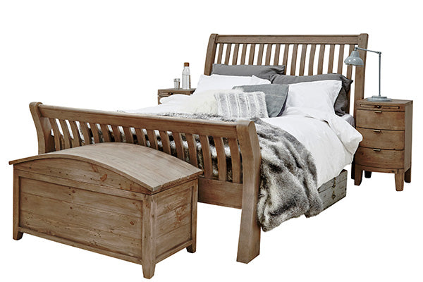 Reclaimed wood bed with white bed sheets and a wooden blanket box and bedside table
