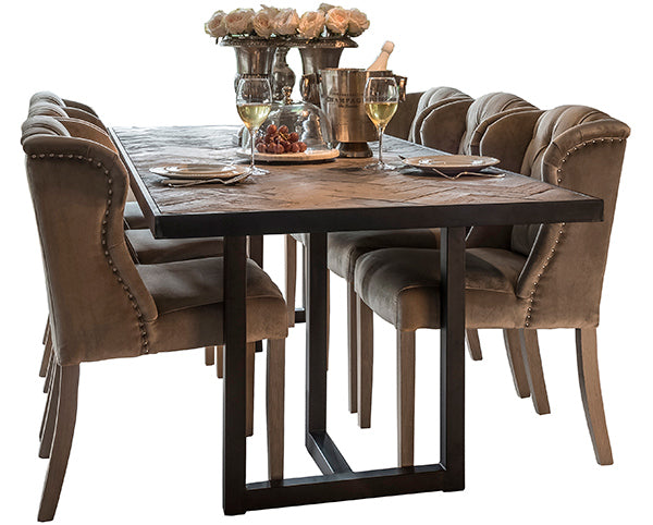 An industrial dining table made of reclaimed oak with dining chairs and flowers on top