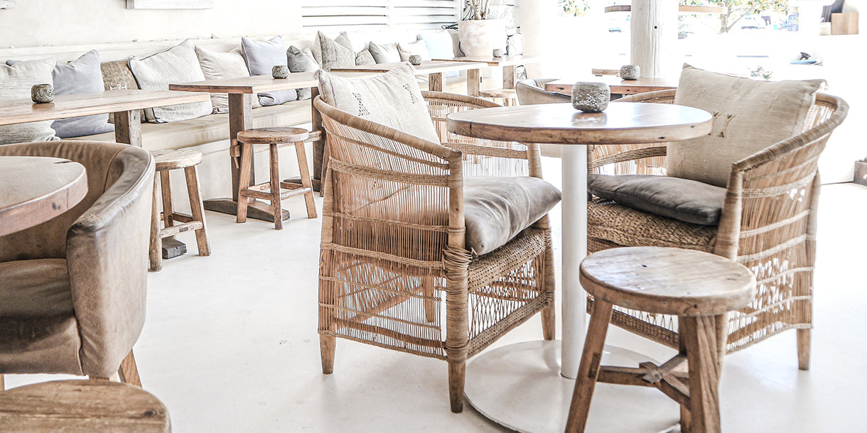 Rattan chairs positioned around wooden stools and tables in a bohemian cafe