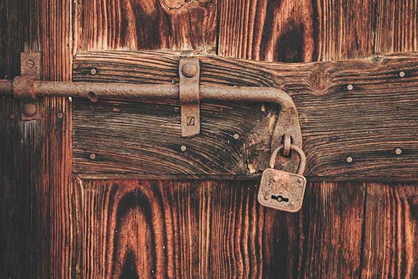 An old wooden door with a brown padlock 