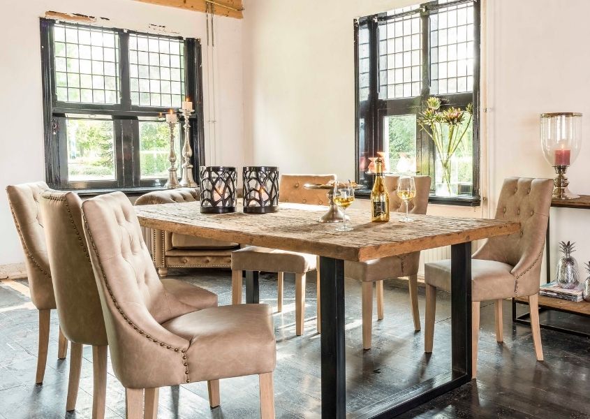 Industrial reclaimed wood dining table with fabric dining chairs and wine glasses on top