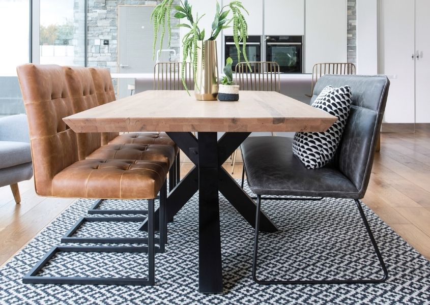 Industrial dining table with black steel spider leg, brown leather dining chairs and grey faux leather dining bench style with black and white rug