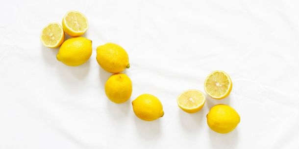 Whole lemons and halved lemons on white surface