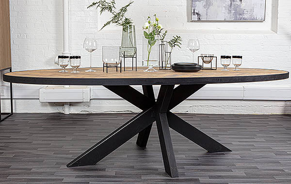 Oval oak dining table on steel legs with greenery and tableware on top