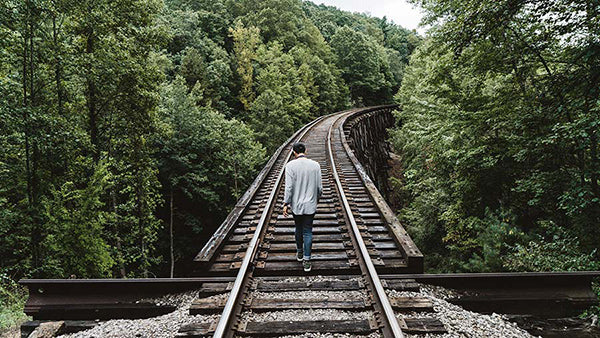 Man walking on wooden railway in the middle of the forest