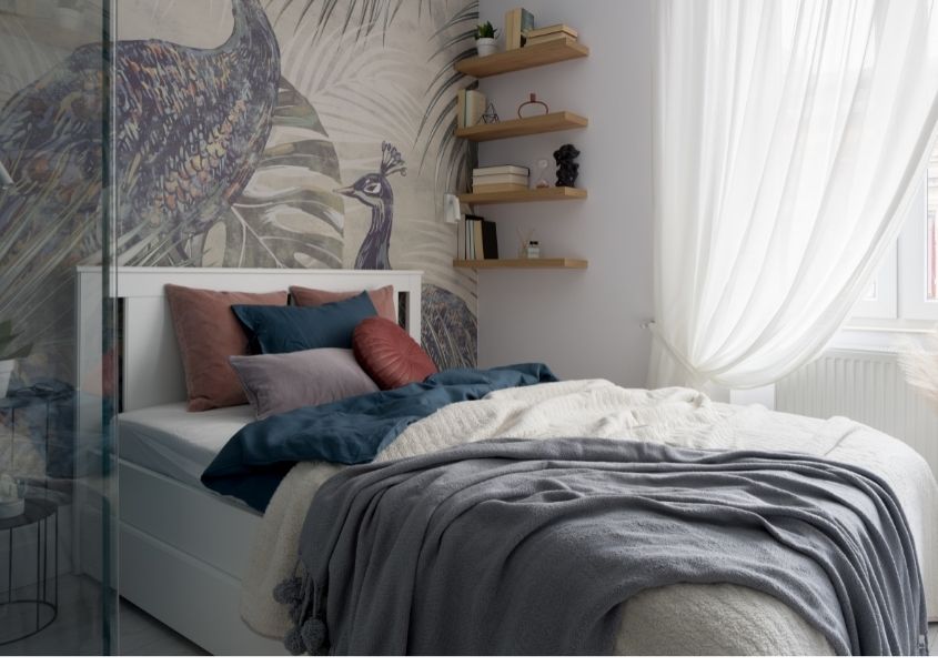 small bedroom with peacock wallpaper and grey covers