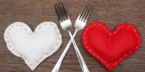 A red and white handstitched fabric heart with two silver forks