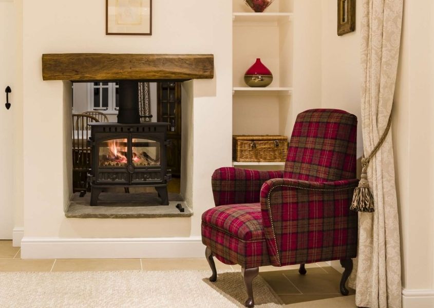 open fireplace with wood burner and red fabric armchair