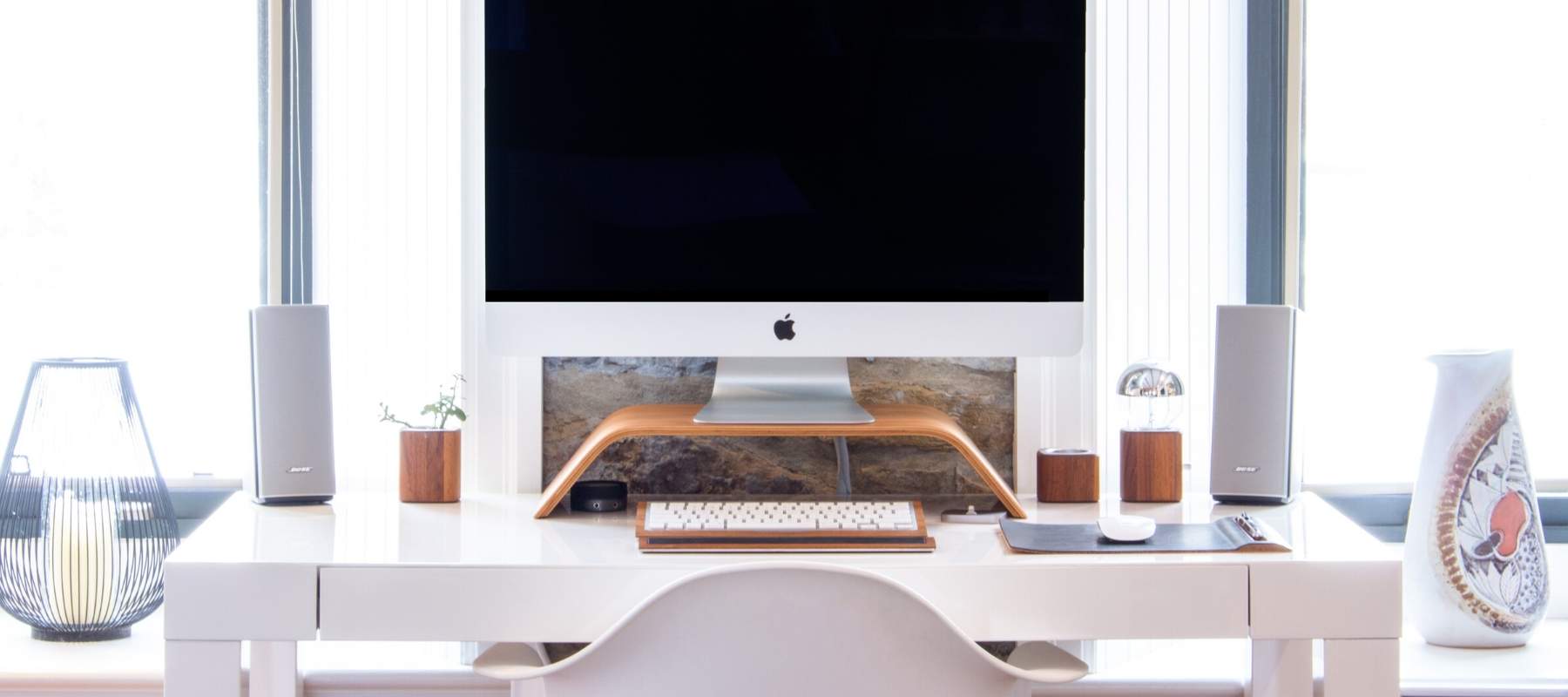 Mac on white desk in front of window
