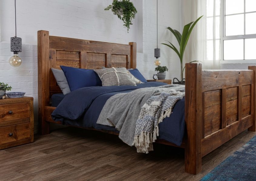 reclaimed wooden bed frame with blue covers and wooden bedside table