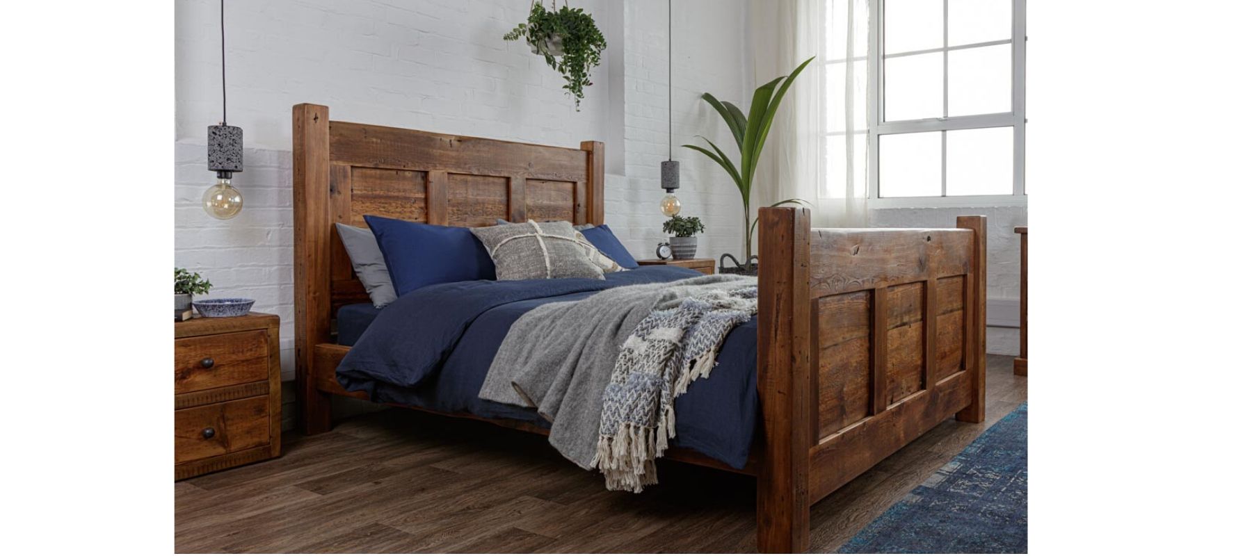 Reclaimed wood bed against white brick wall