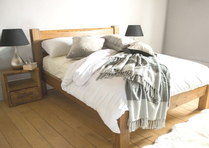 Reclaimed wood bed frame with white covers and grey wool blanket thrown over bed